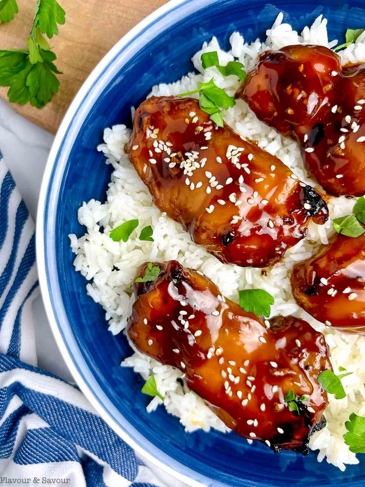 Teriyaki chicken thighs brushed with teriyaki glaze in a bowl with rice.