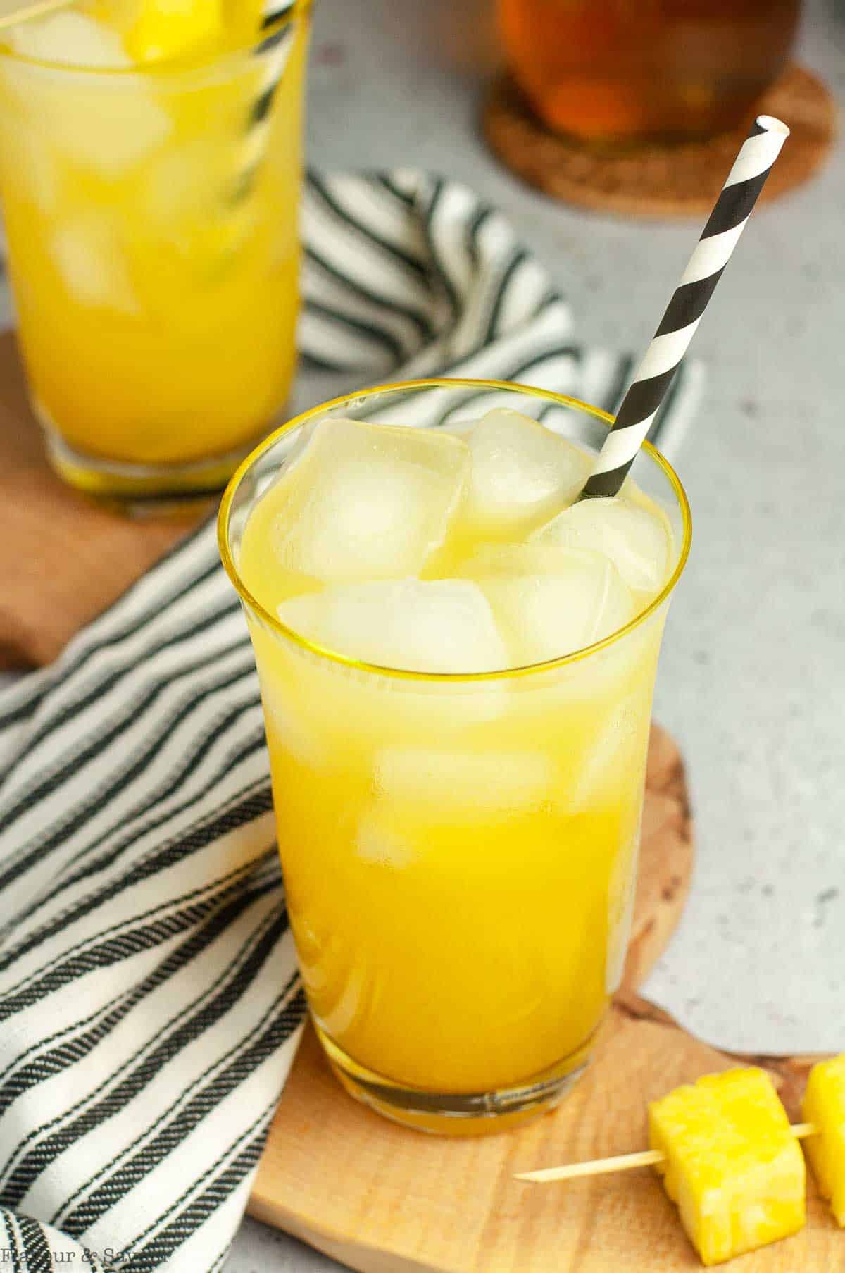 Tall ice-filled glasses with pineapple ginger beer mocktail.