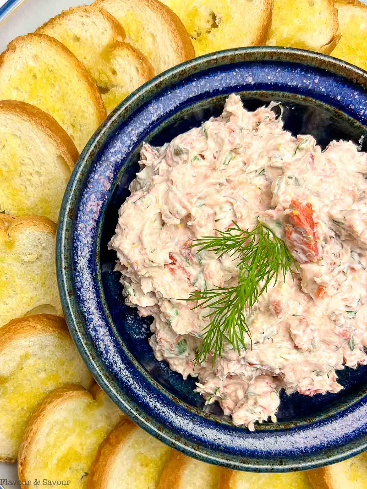 Close up view of a bowl of smoked salmon dip garnished with a sprig of dill.