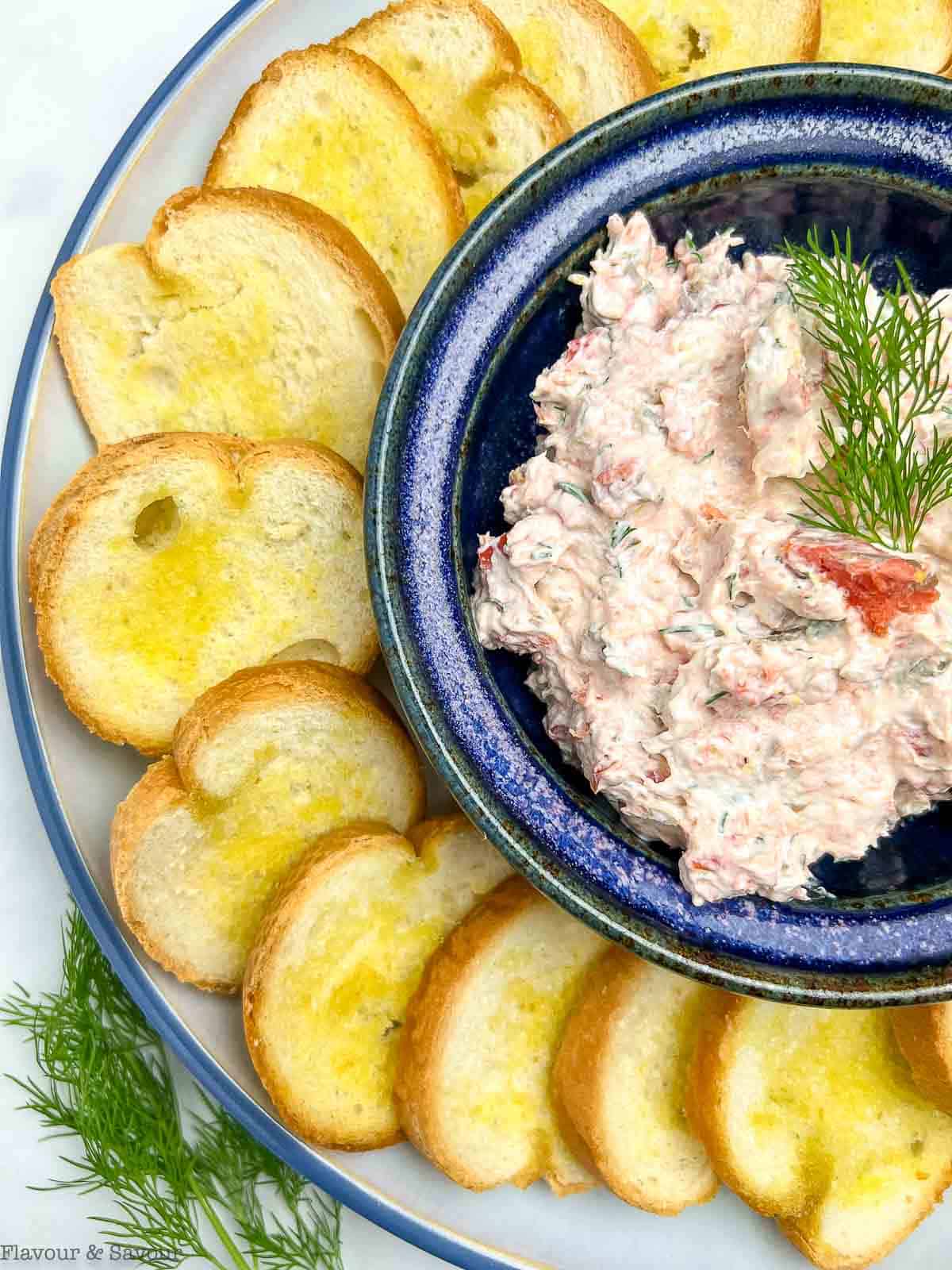 Smoked salmon dip in a bowl surrounded by crostini.