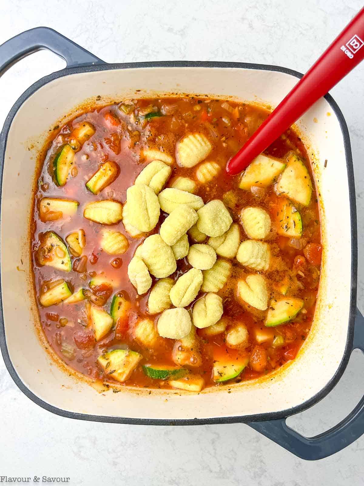 Adding gnocchi to vegetable soup.