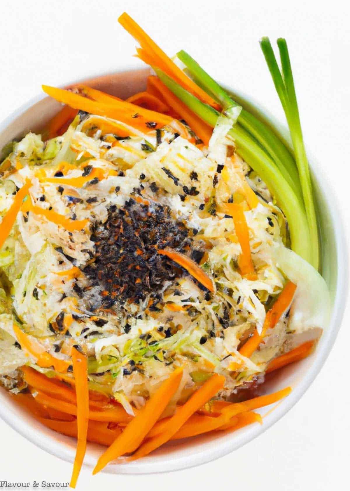 A bowl of Thai-style coleslaw with shredded cabbage, carrots, kohlrabi and green onions.