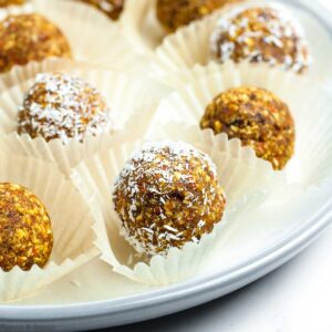 Carrot cake energy bites in small cake cases on a plate.