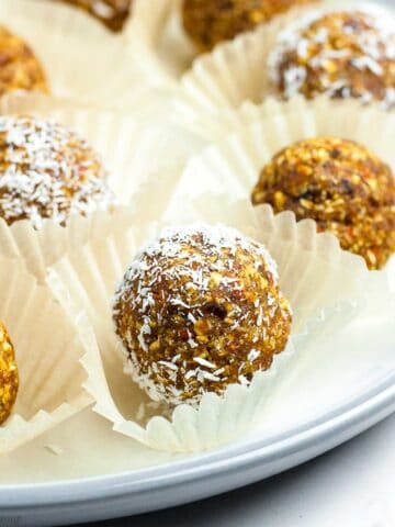 Carrot cake energy bites in small cake cases on a plate.