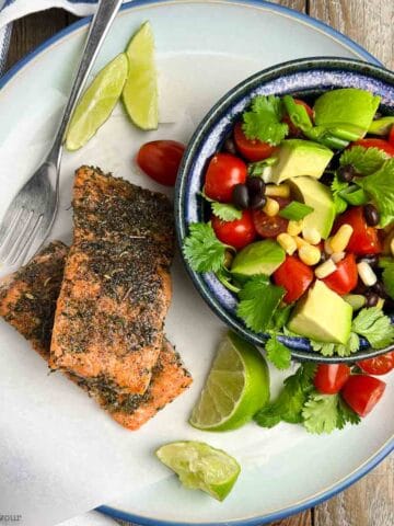 Jerk salmon fillets beside a bowl of black bean salad.