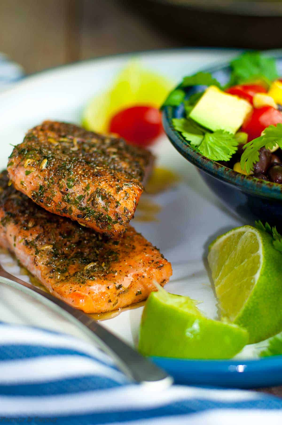 Jerk salmon and black bean salad with lime wedges.