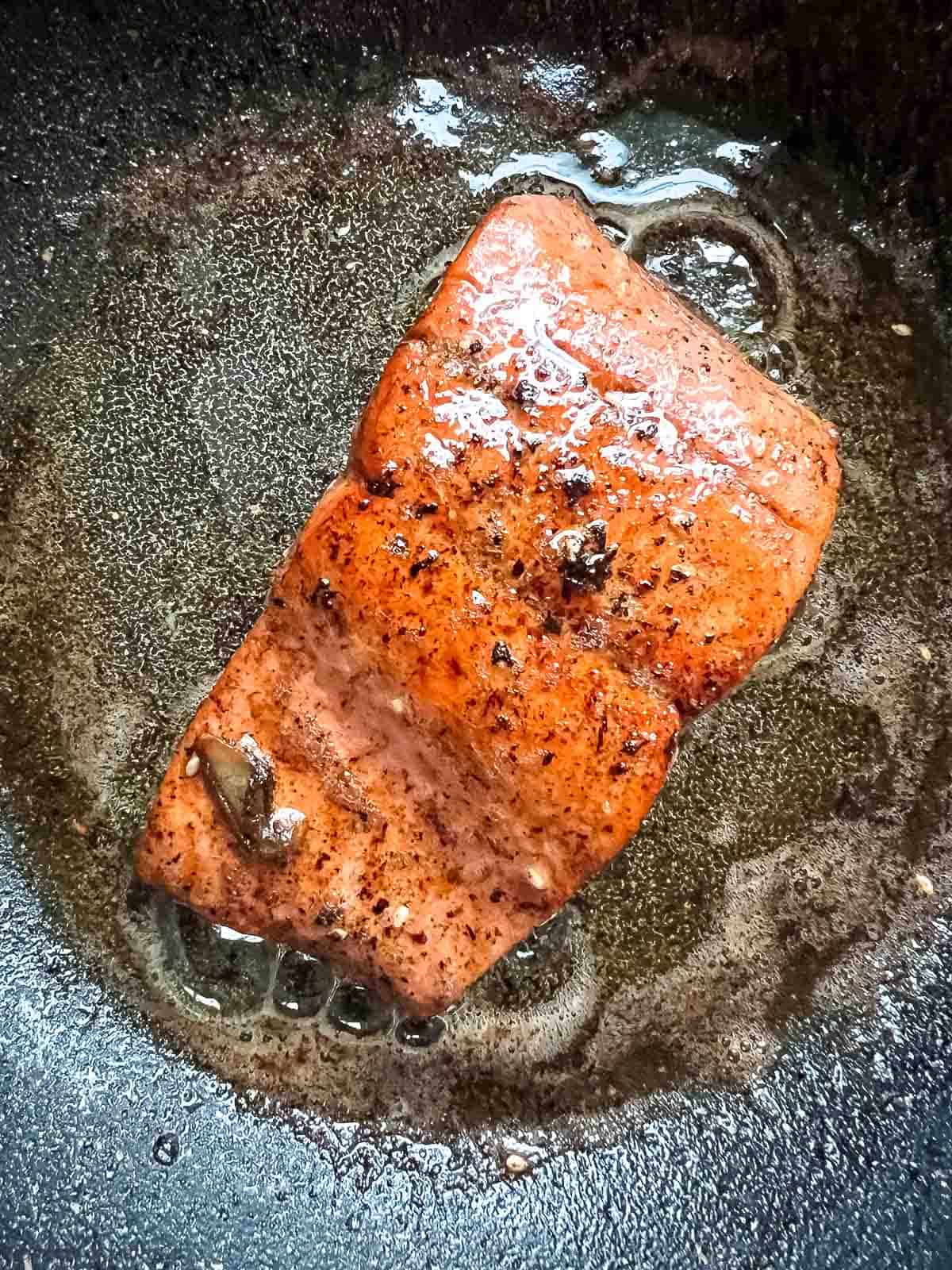 Seared salmon in a skillet.