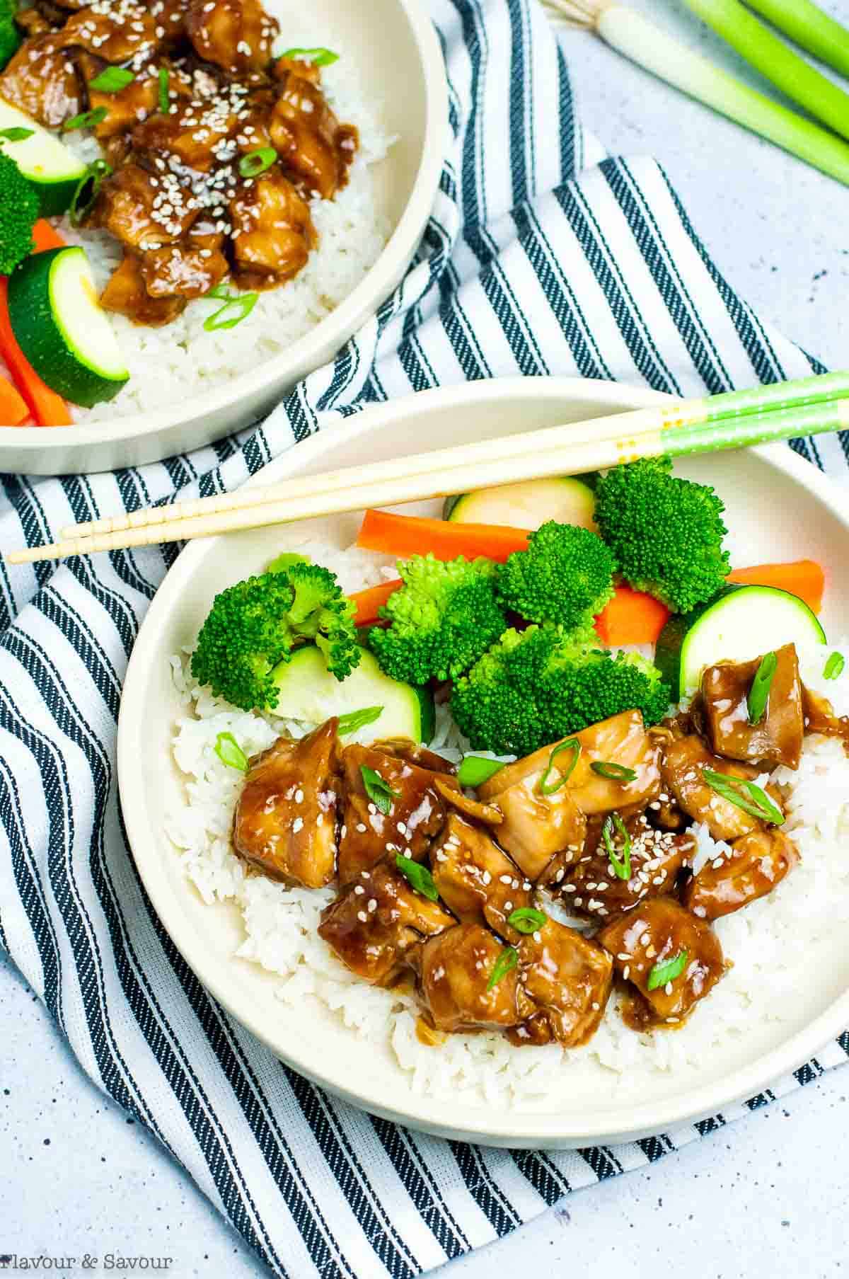 Two bowls of teriyaki chicken with rice and vegetables.