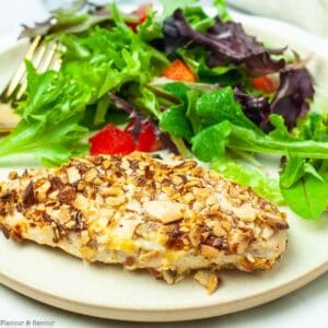An air-fried almond-crusted chicken breast on a plate with a green salad.