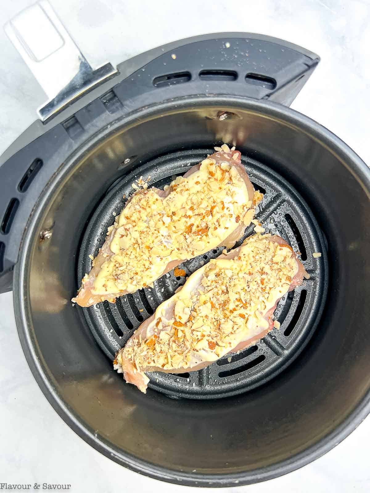 Almond-crusted chicken breasts in an air fryer basket.