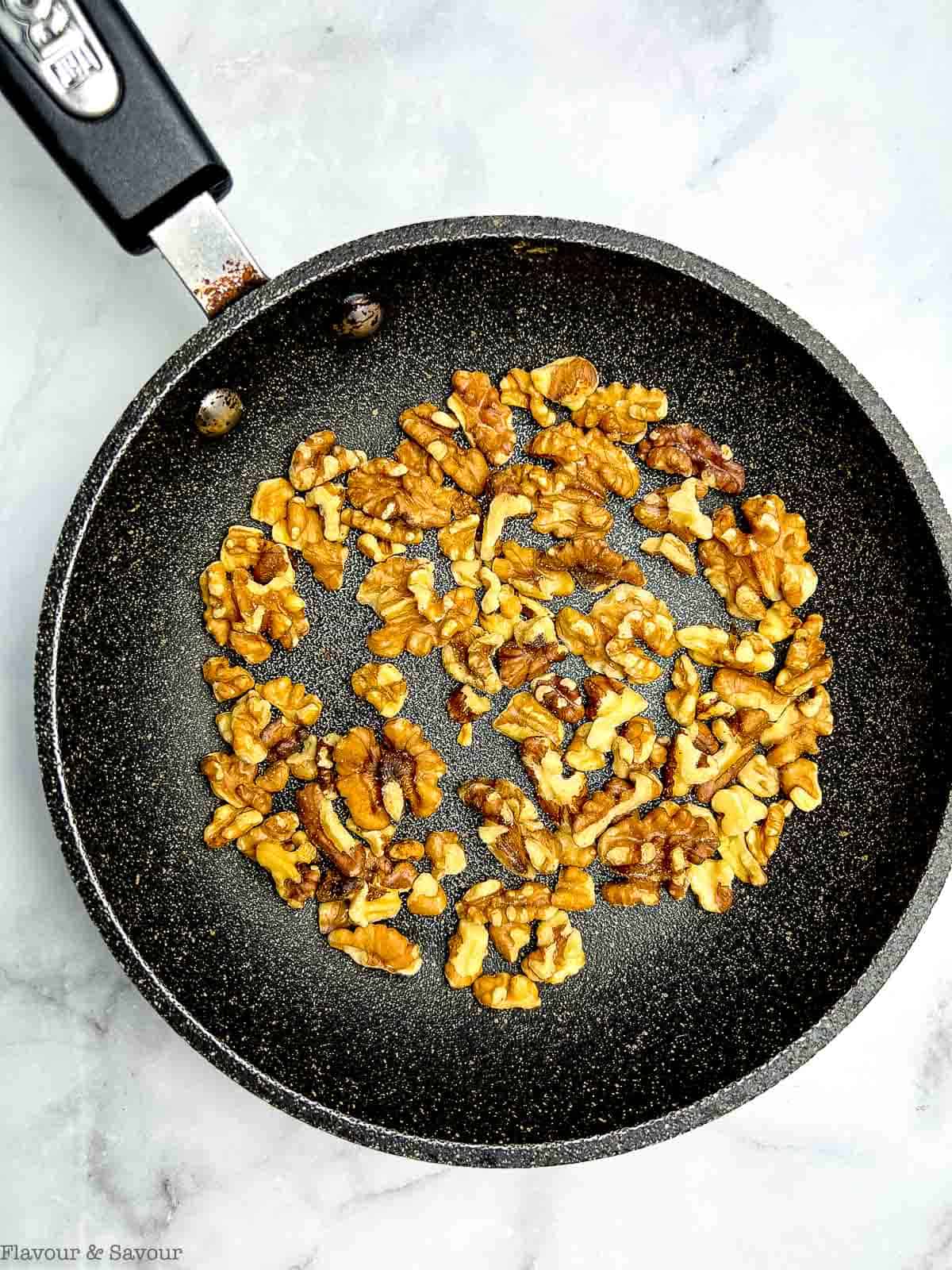 Toasting walnuts in a skillet for arugula pear salad.