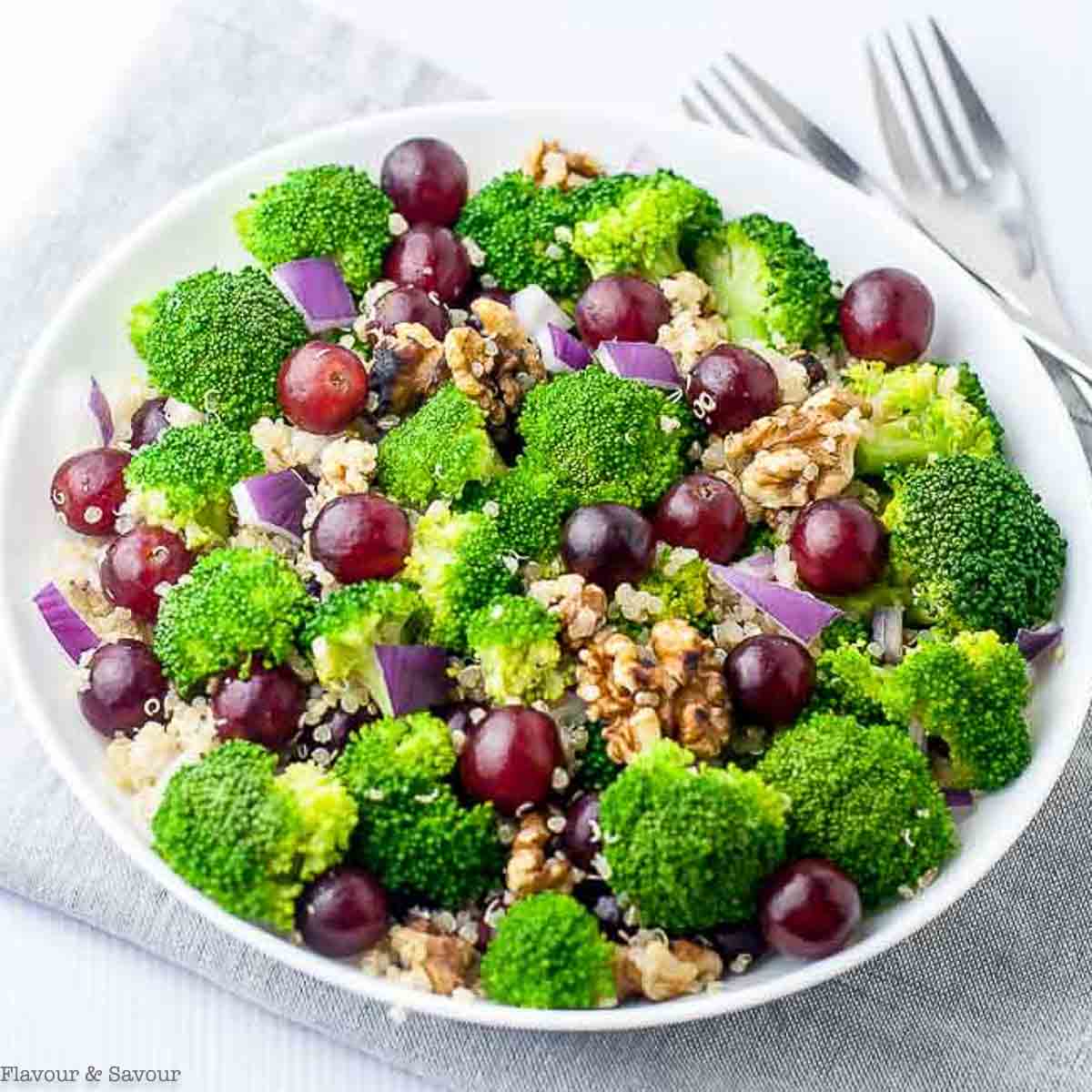 Overhead view of a quinoa salad with grapes, walnuts and broccoli florets.