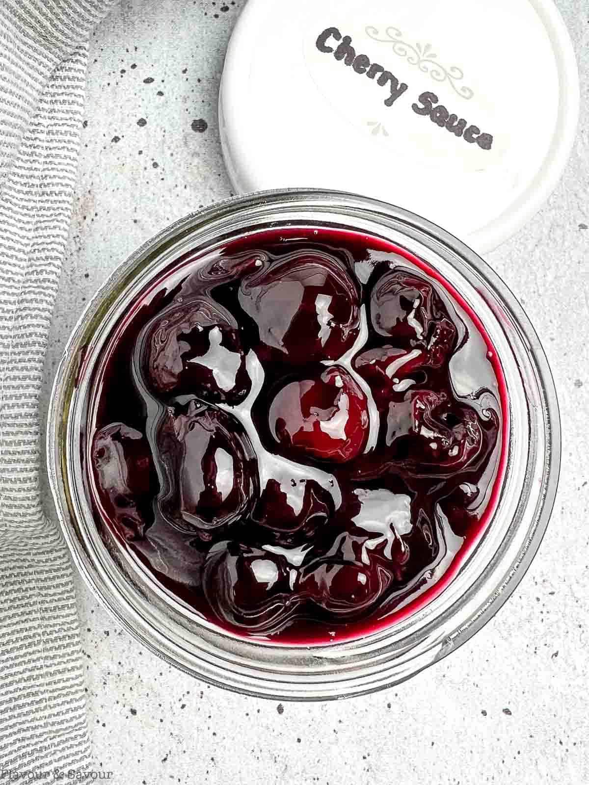 Overhead view of a jar filled with homemade cherry sauce.