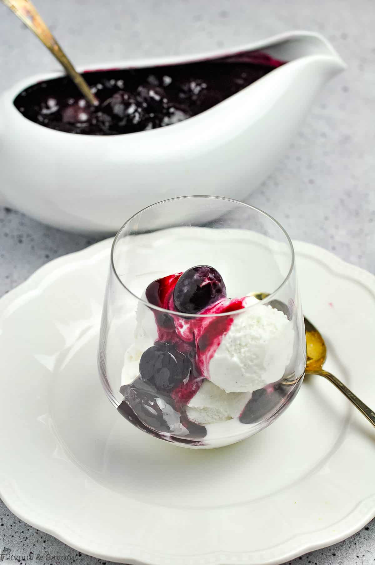 A dessert glass with ice cream with cherry sauce.