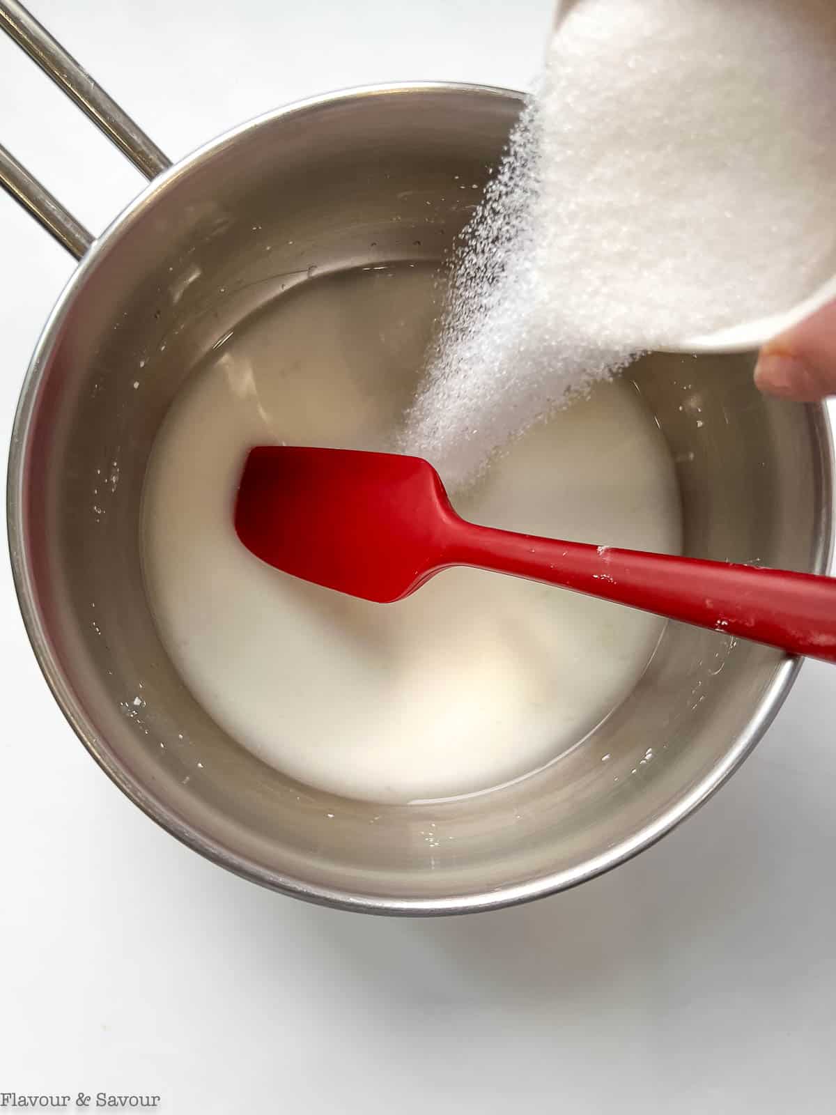 Adding sugar to cornstarch, water and lemon juice in a saucepan.