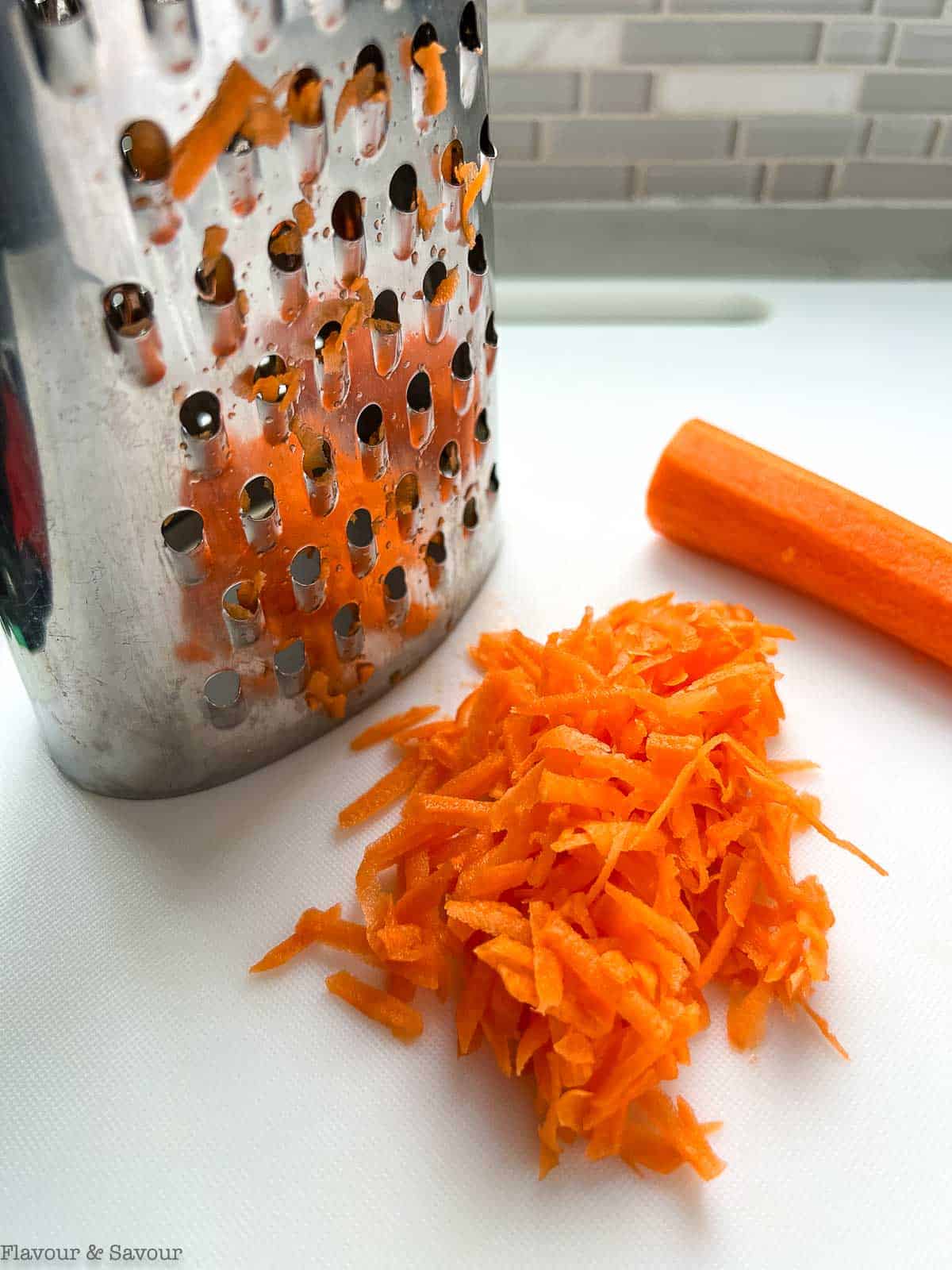 A box grater and grated carrots.