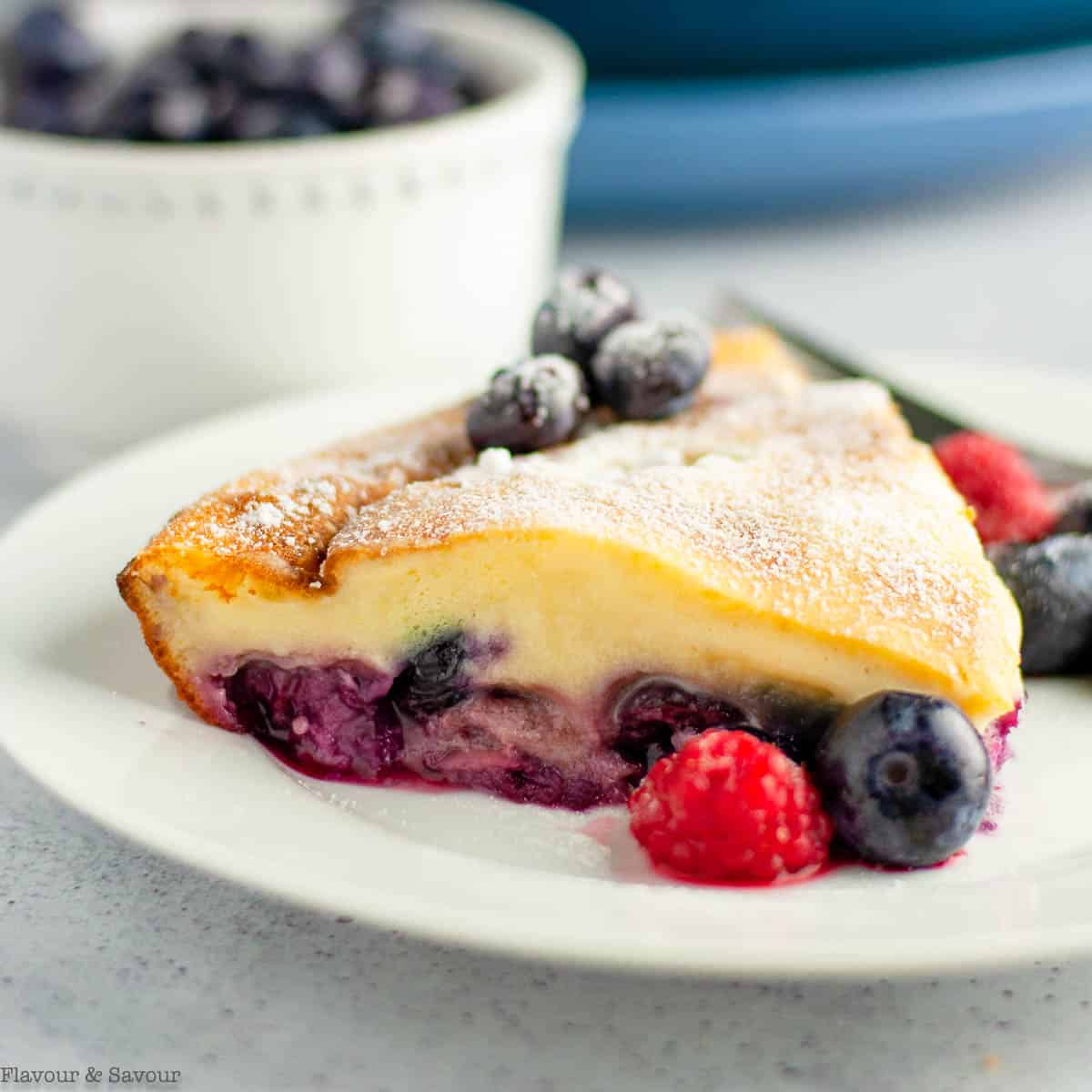 Close up view of a slice of berry clafoutis with cherries.