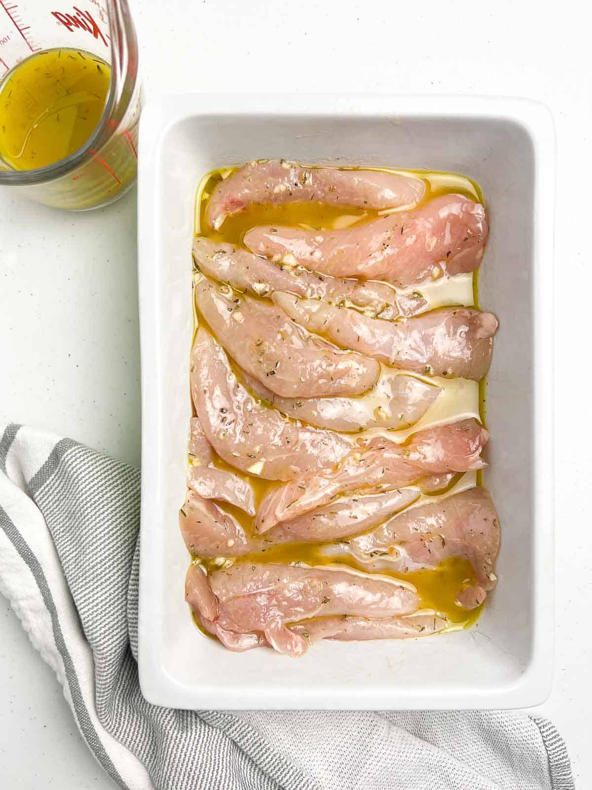 Chicken tenders marinating in Greek lemon garlic marinade.