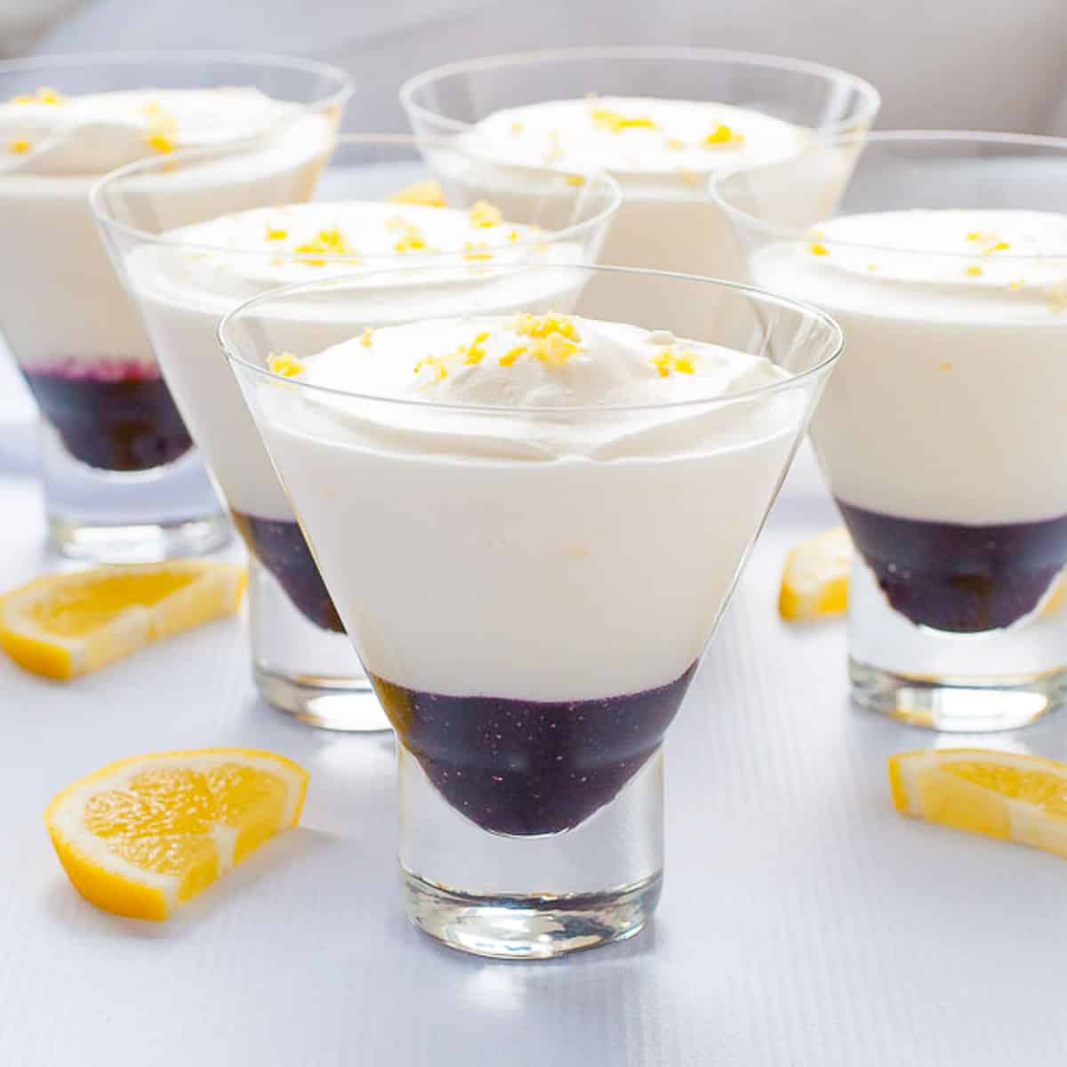 Lemon mousse in dessert glasses with blueberry sauce.