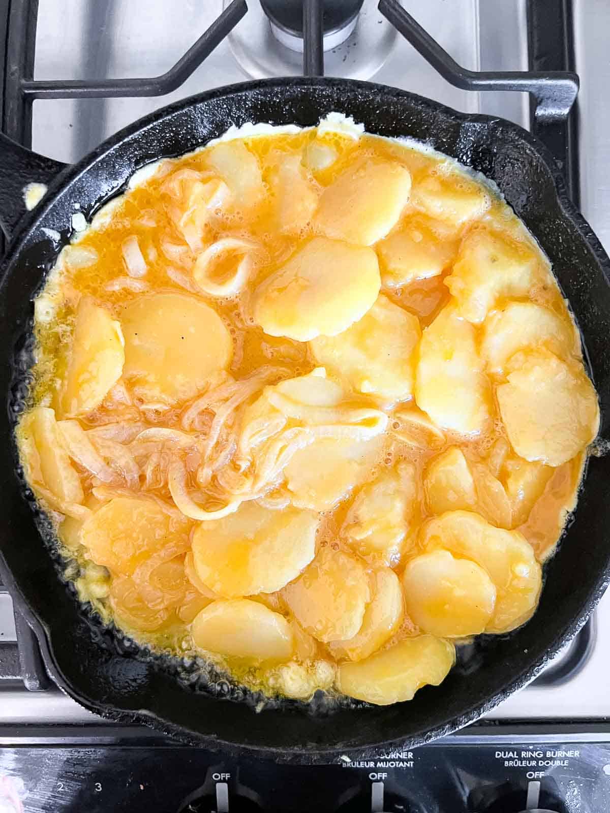 Spanish tortilla mixture in a cast iron skillet on the stove top.