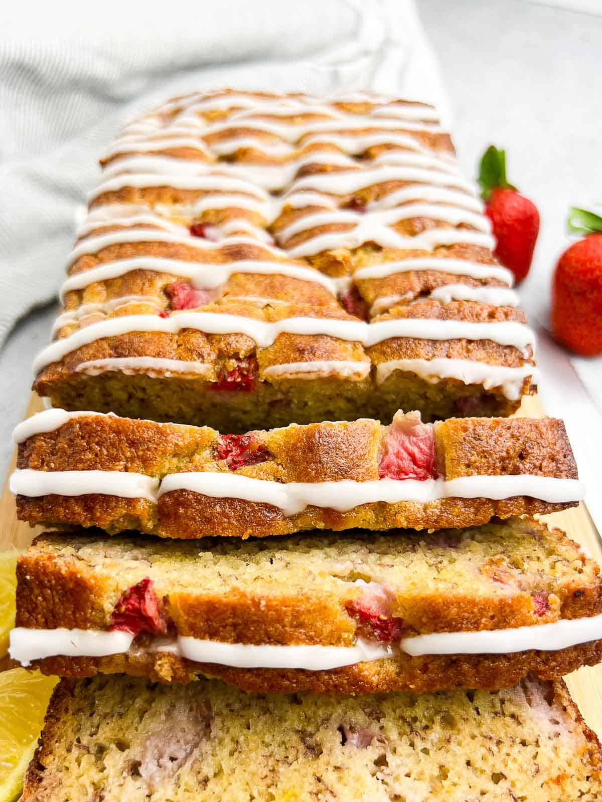 Close up view of gluten-free almond flour strawberry banana bread drizzled with lemon glaze.