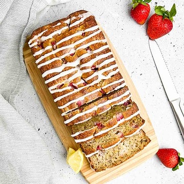 Overhead view of a sliced loaf of almond flour banana bread with strawberries.