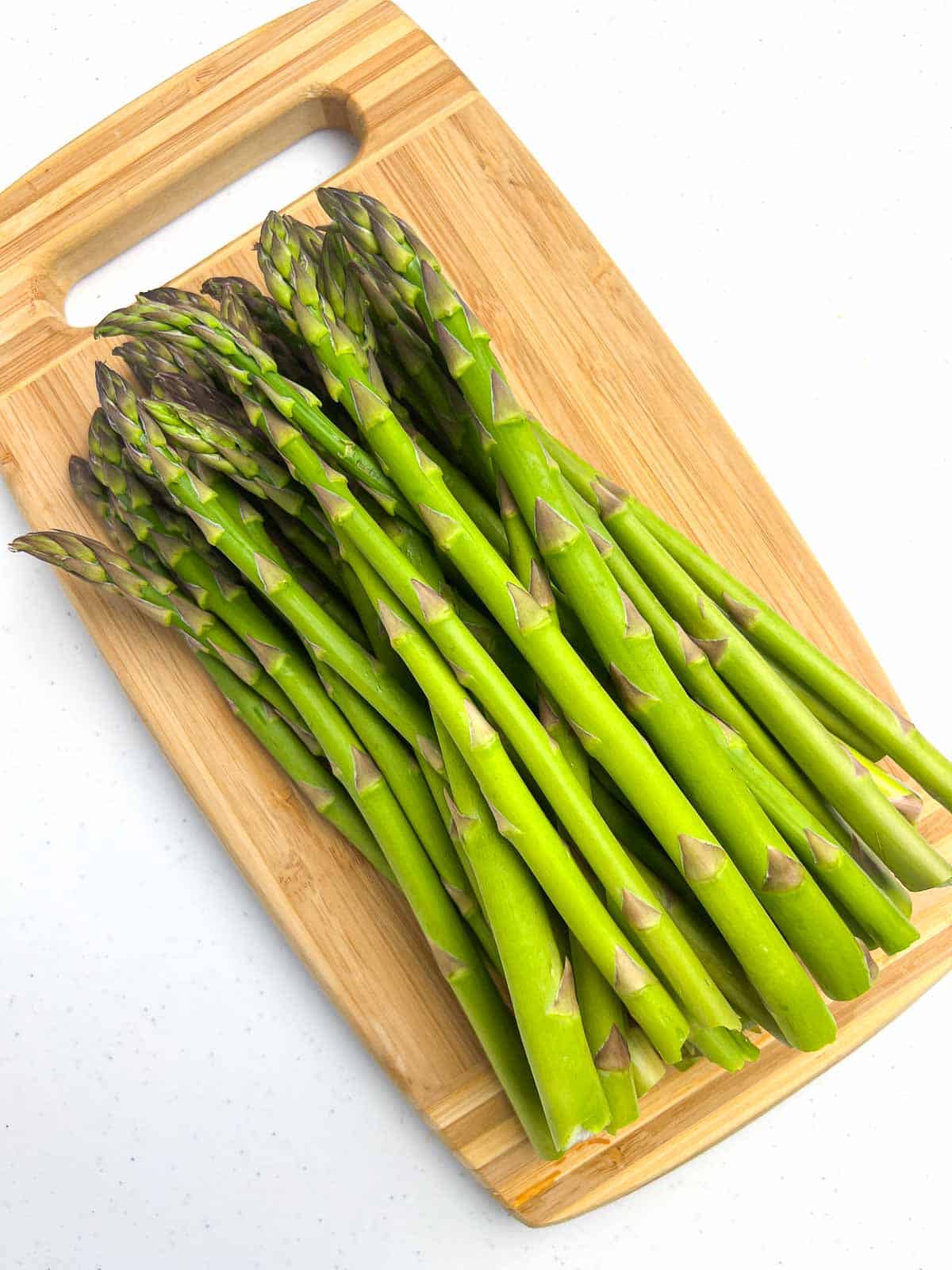 Fresh asparagus spears with ends trimmed on a cutting board.