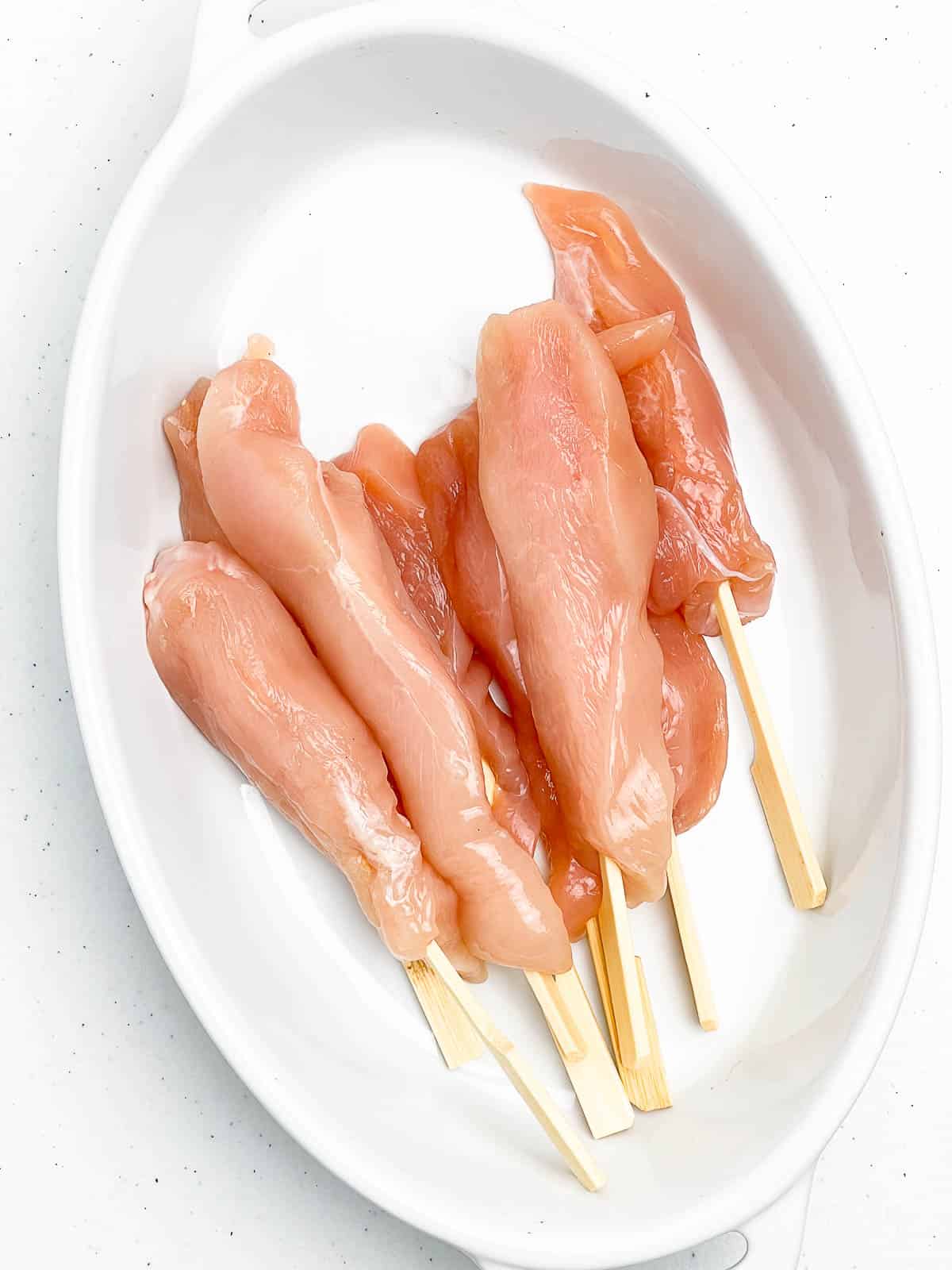 Raw chicken on bamboo skewers for simple chicken satay.