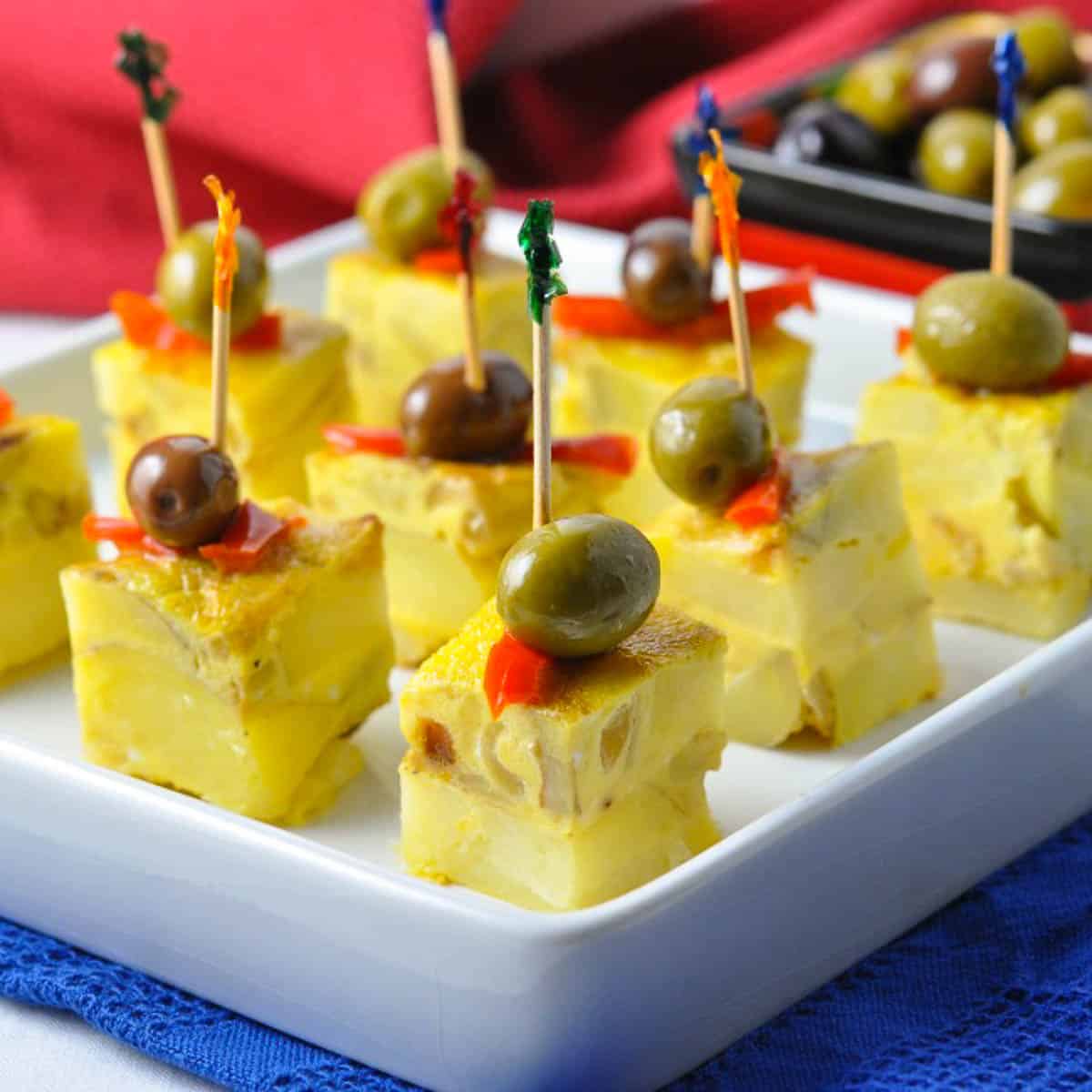 Small cubes of tortilla española served as tapas with Spanish olives on toothpicks.
