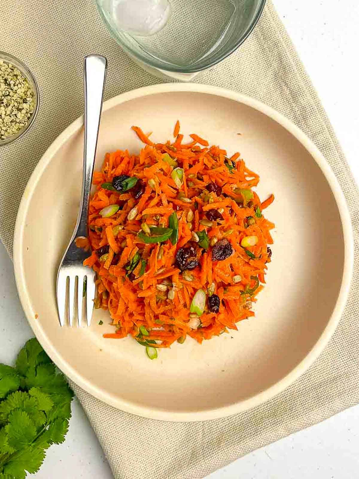 Raw Carrot Salad with raisins in a bowl with a fork.