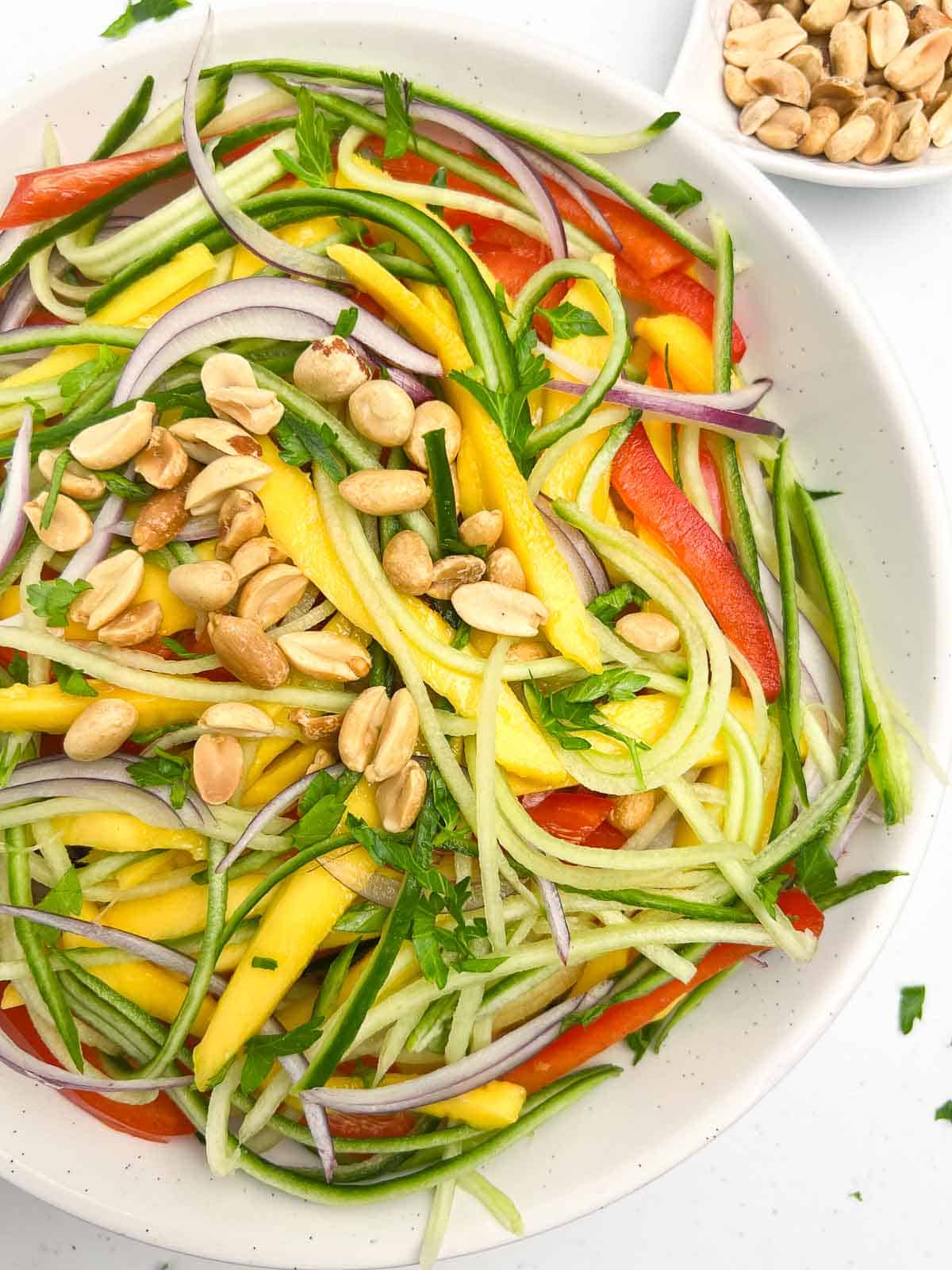 Close up view of a bowl of Thai mango salad with peanuts.