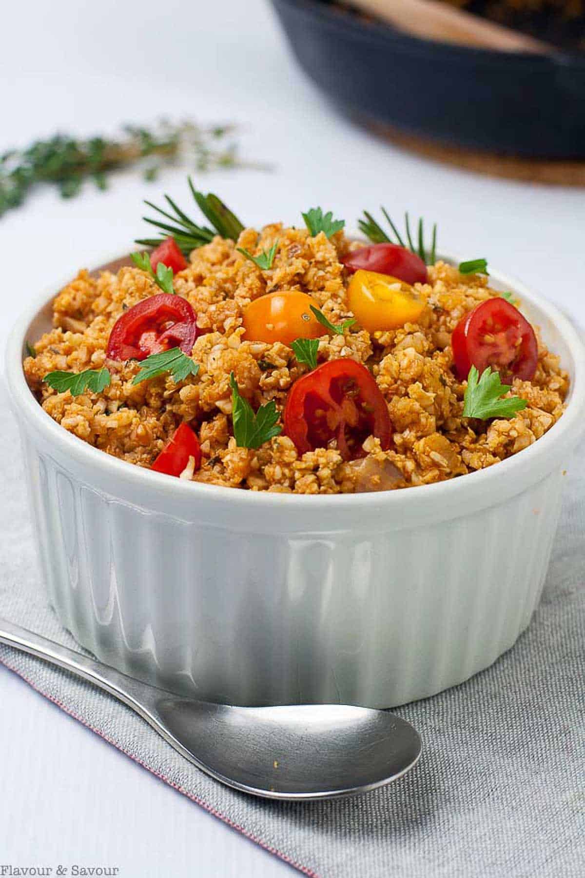 A bowl of Spanish-style cauliflower rice with cherry tomatoes and herbs.