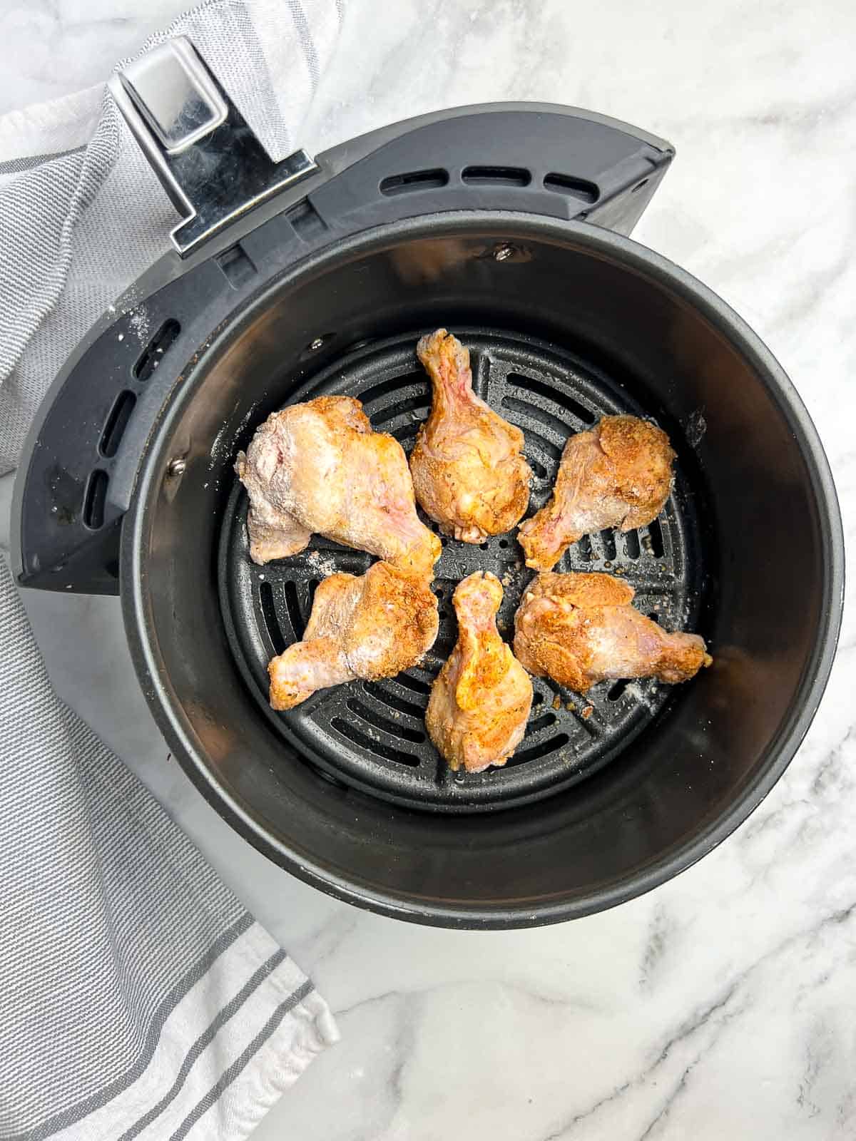 Chicken drumettes arranged in a single layer in an air fryer basket.