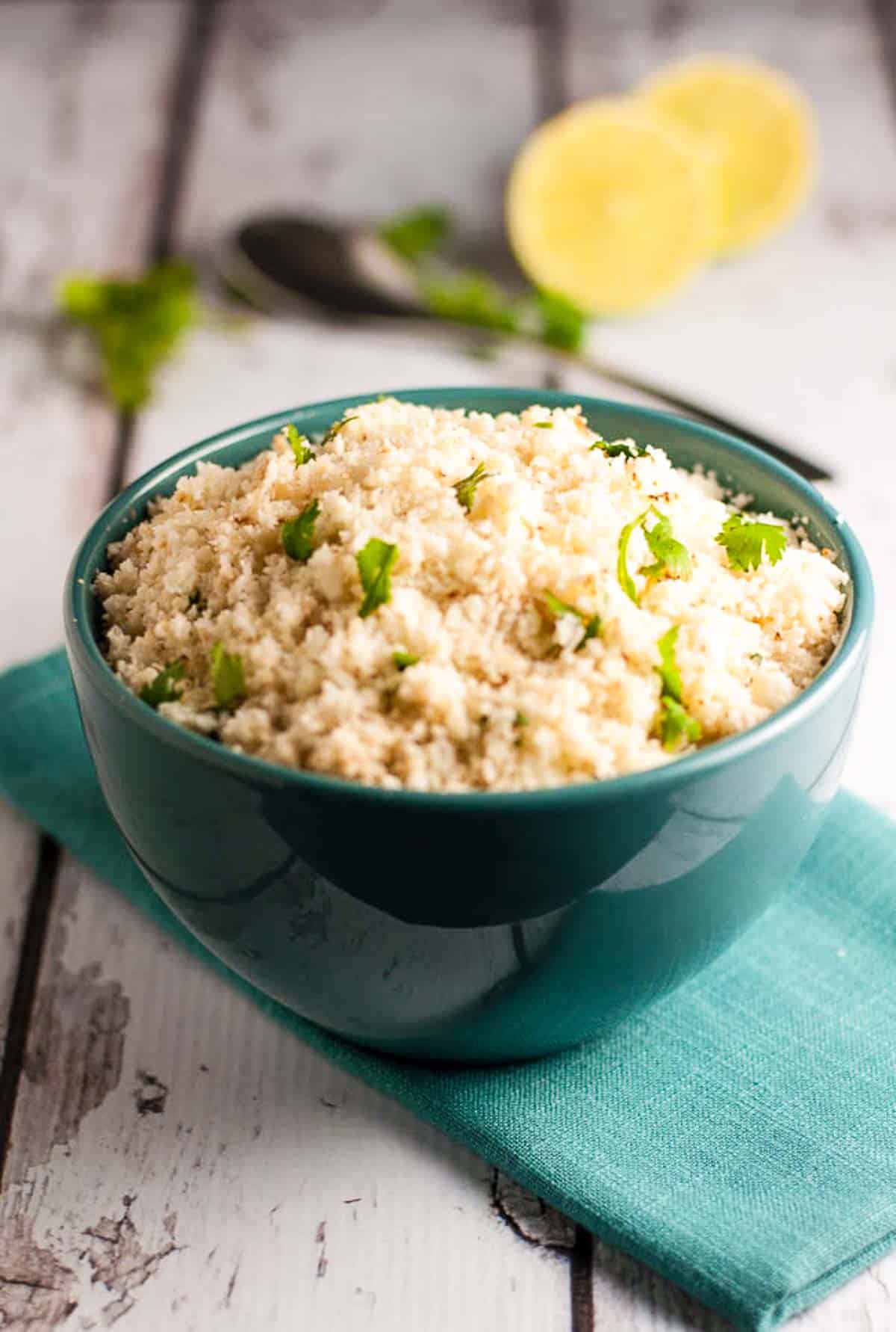 A bowl of cauliflower rice with cilantro and lime.
