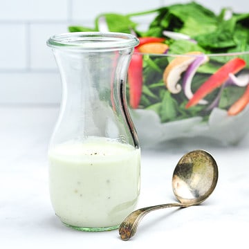 A Weck jar with Greek yogurt Gorgonzola dressing and a salad in the background.