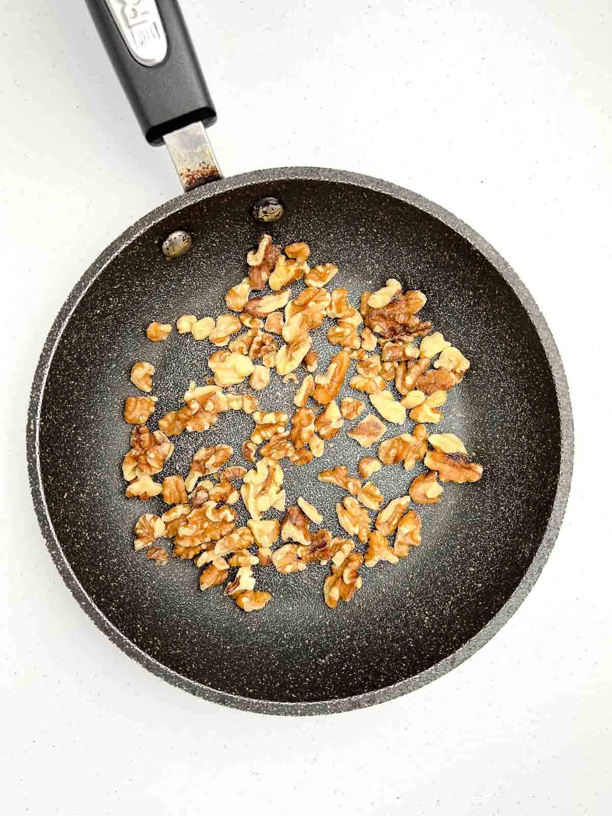 Walnuts toasting in a small skillet.