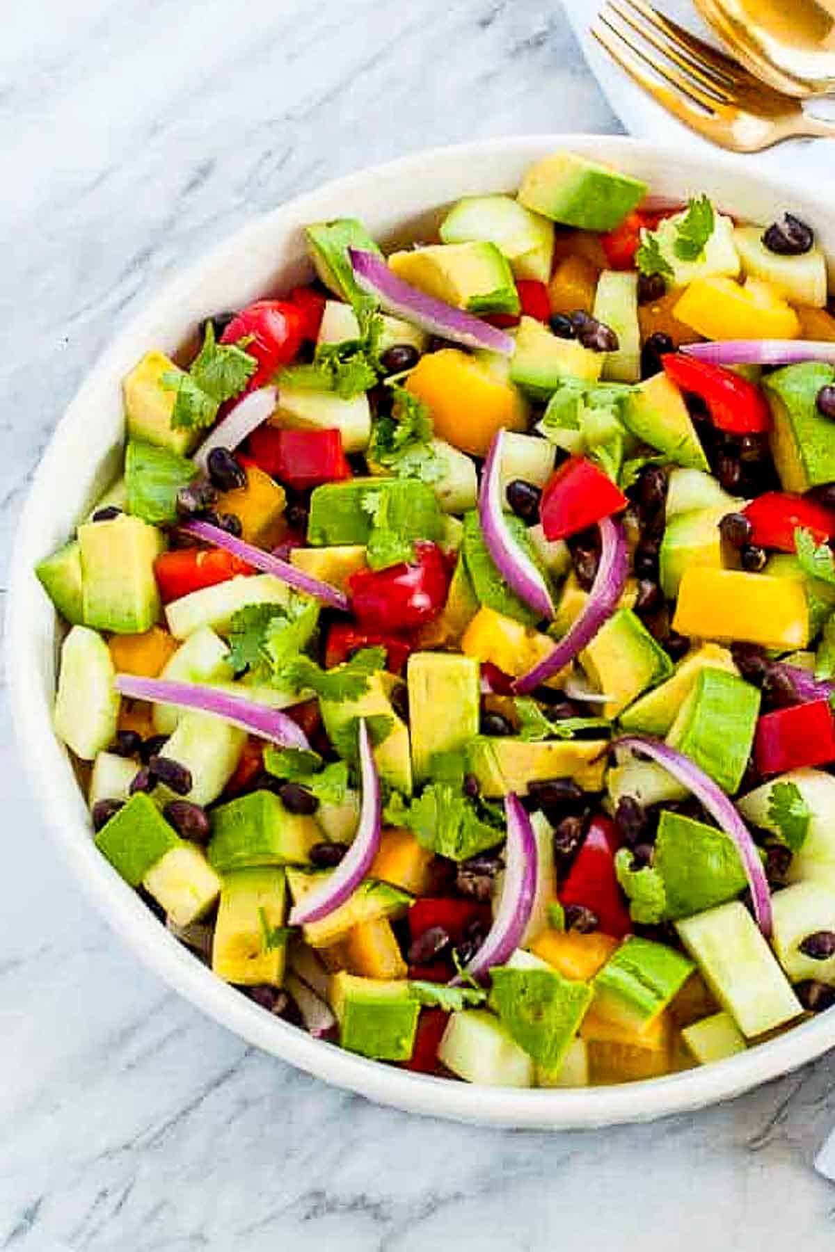 Close up view of a bowl of tomato avocado black bean salad with cilantro lime dressing.