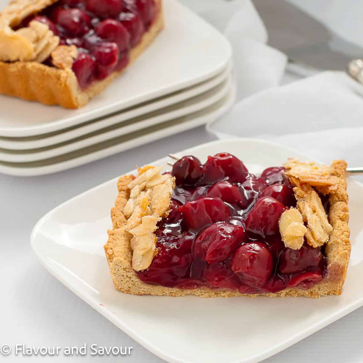 Slices of sour cherry tart on white plates.