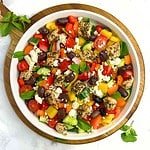 Overhead view of a round shallow bowl with Greek Chicken Salad with Mint leaves.