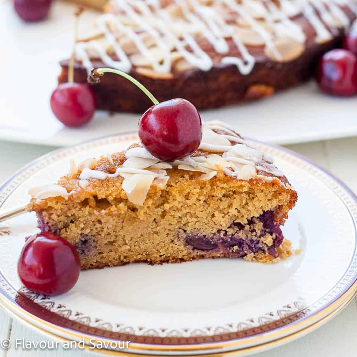 A slice of gluten-free cherry almond ricotta cake with a fresh cherry on top.