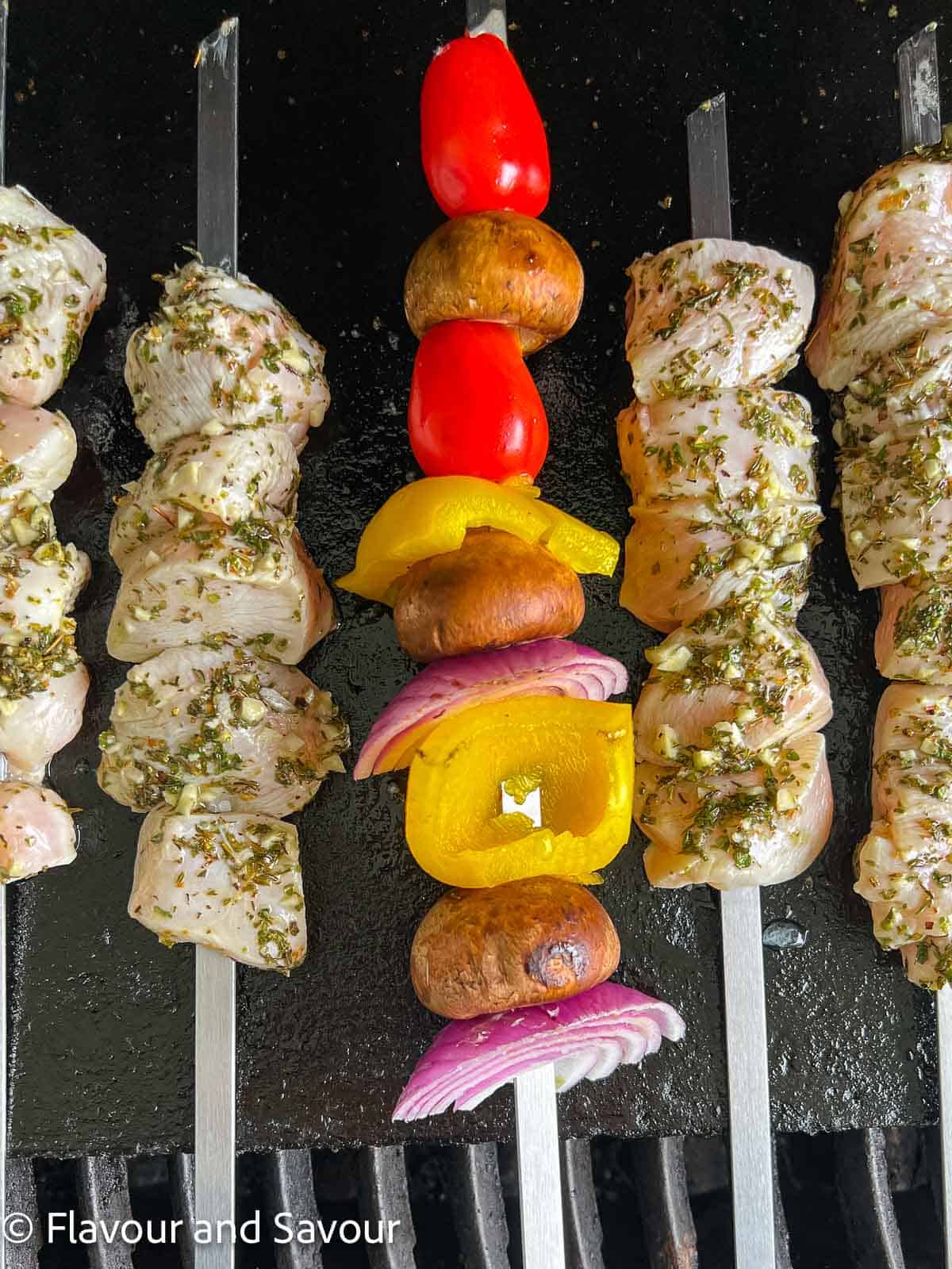 Chicken kabobs on skewers on a grill.