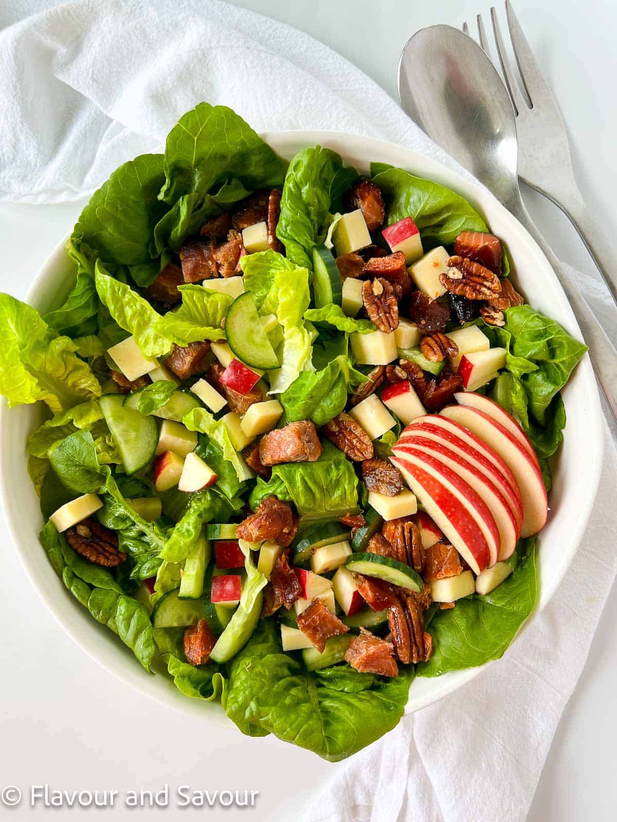 A bowl of smoked salmon salad with apples, cheese, and pecans.