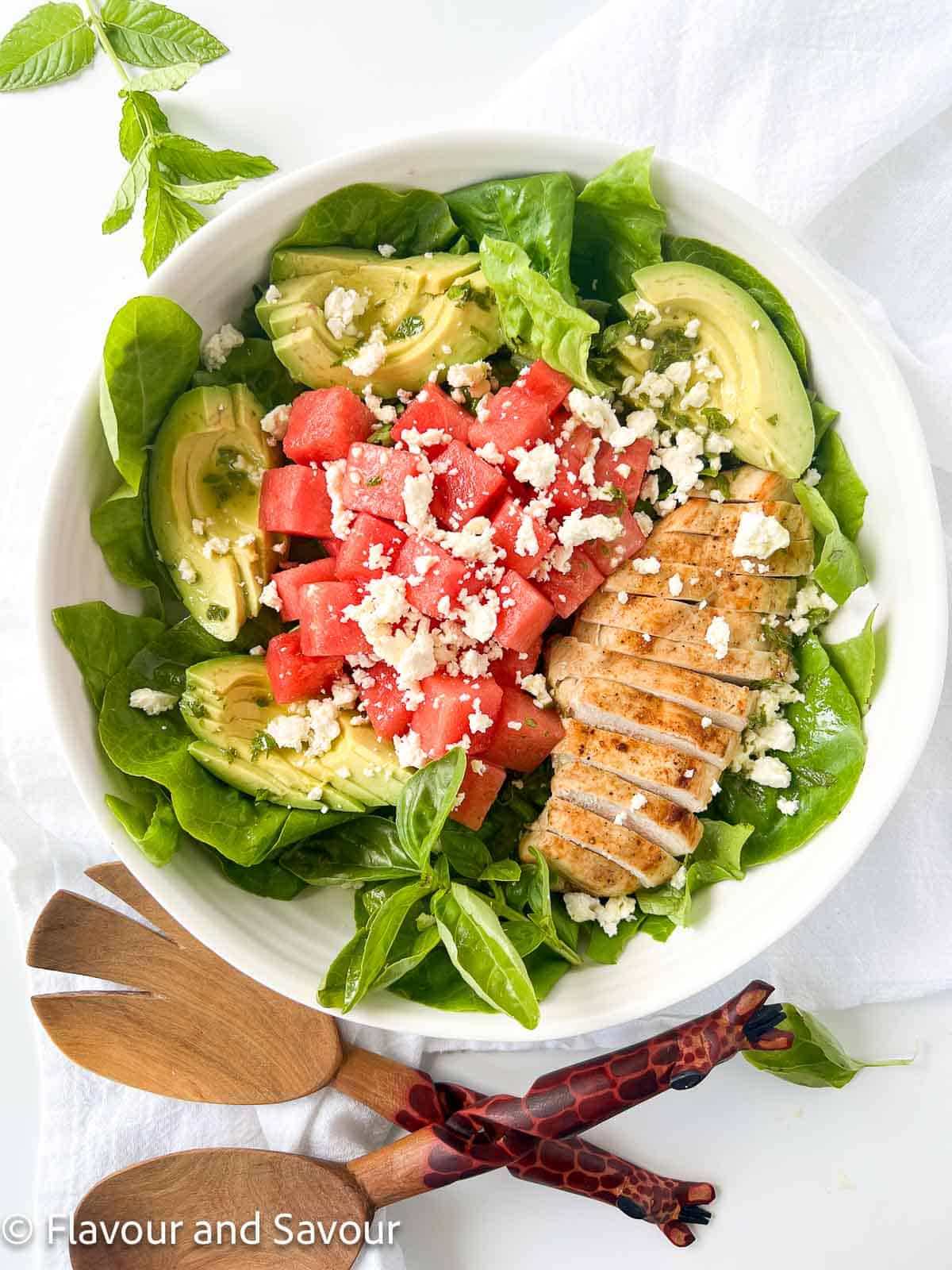 Avocado Chicken Salad with Watermelon in a bowl with a pair of salad servers.