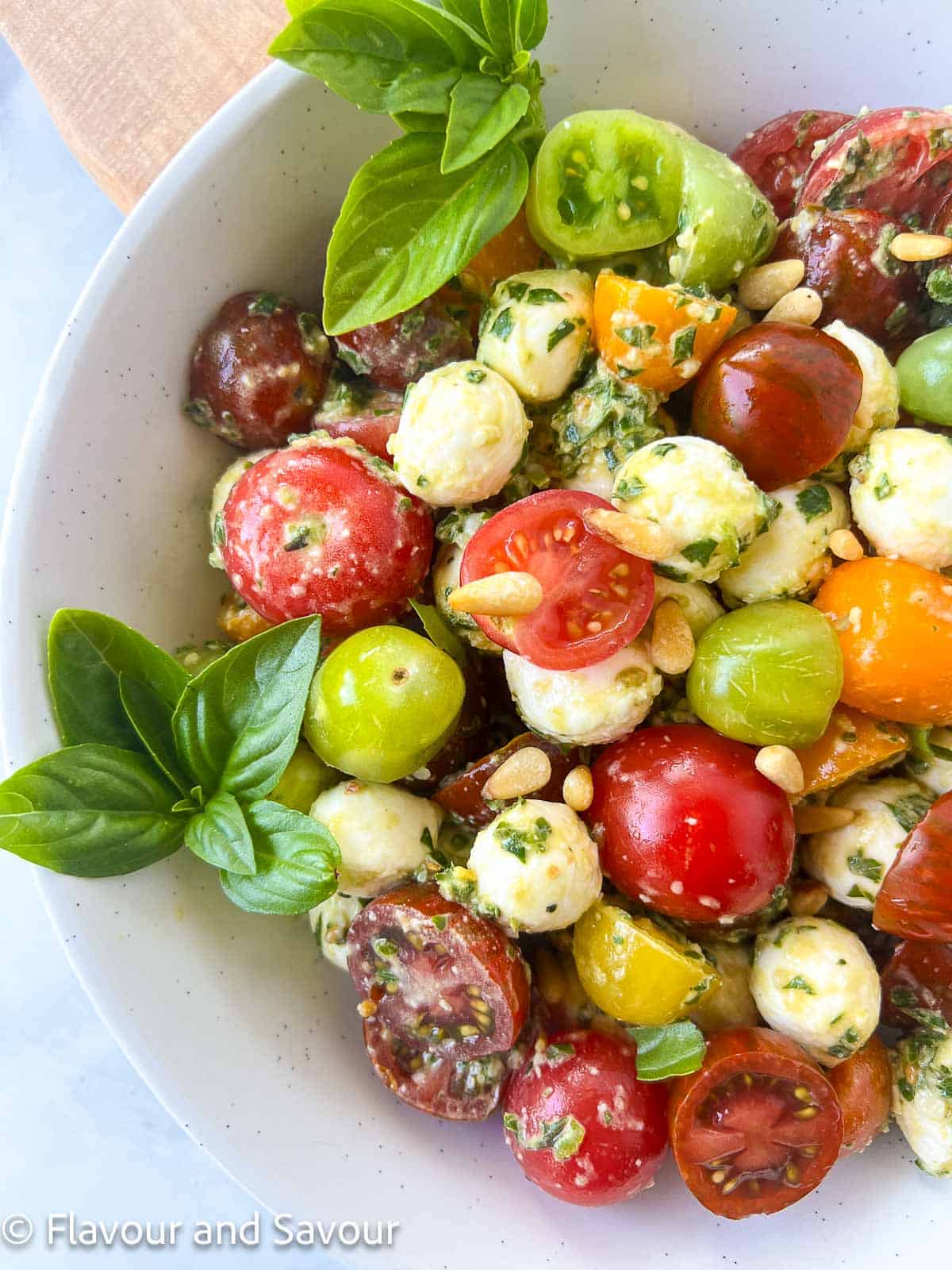 Closeup view of Pesto Caprese Salad made with cherry tomatoes and mini mozzarella balls.