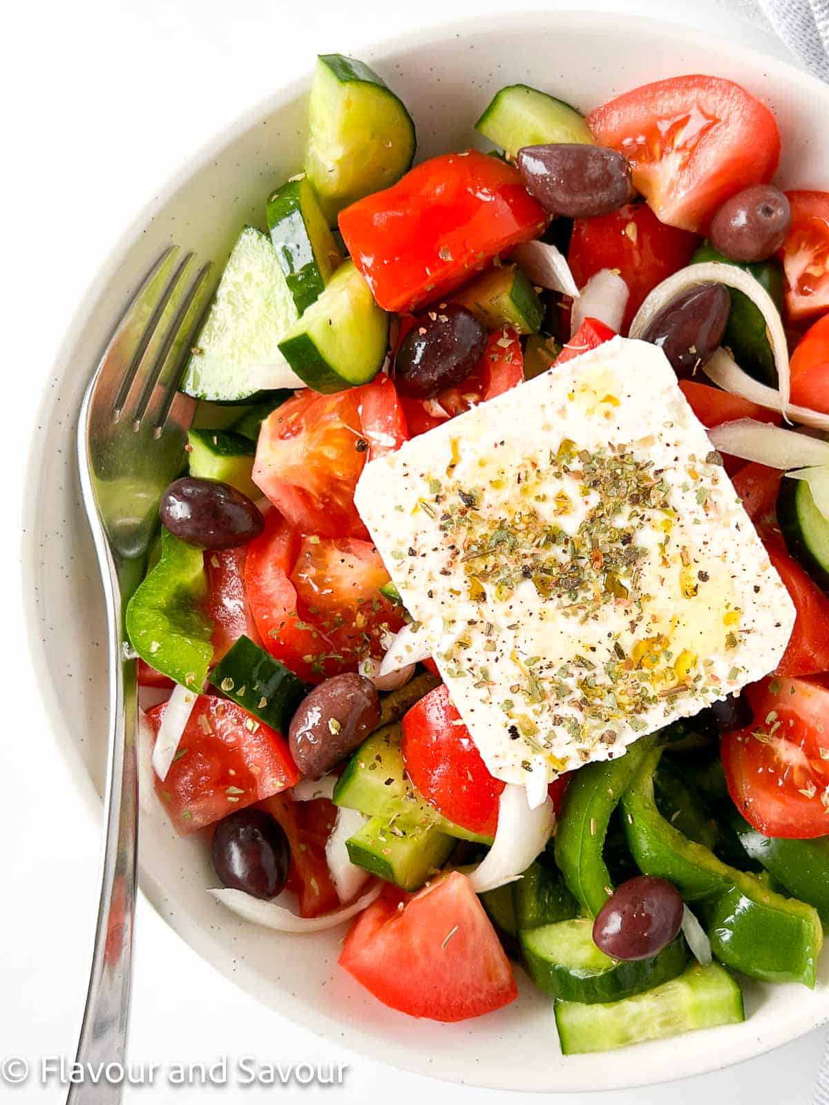 A traditional Greek salad with a slab of feta cheese on top.
