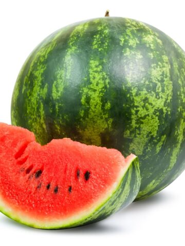 A whole watermelon with a slice beside it.