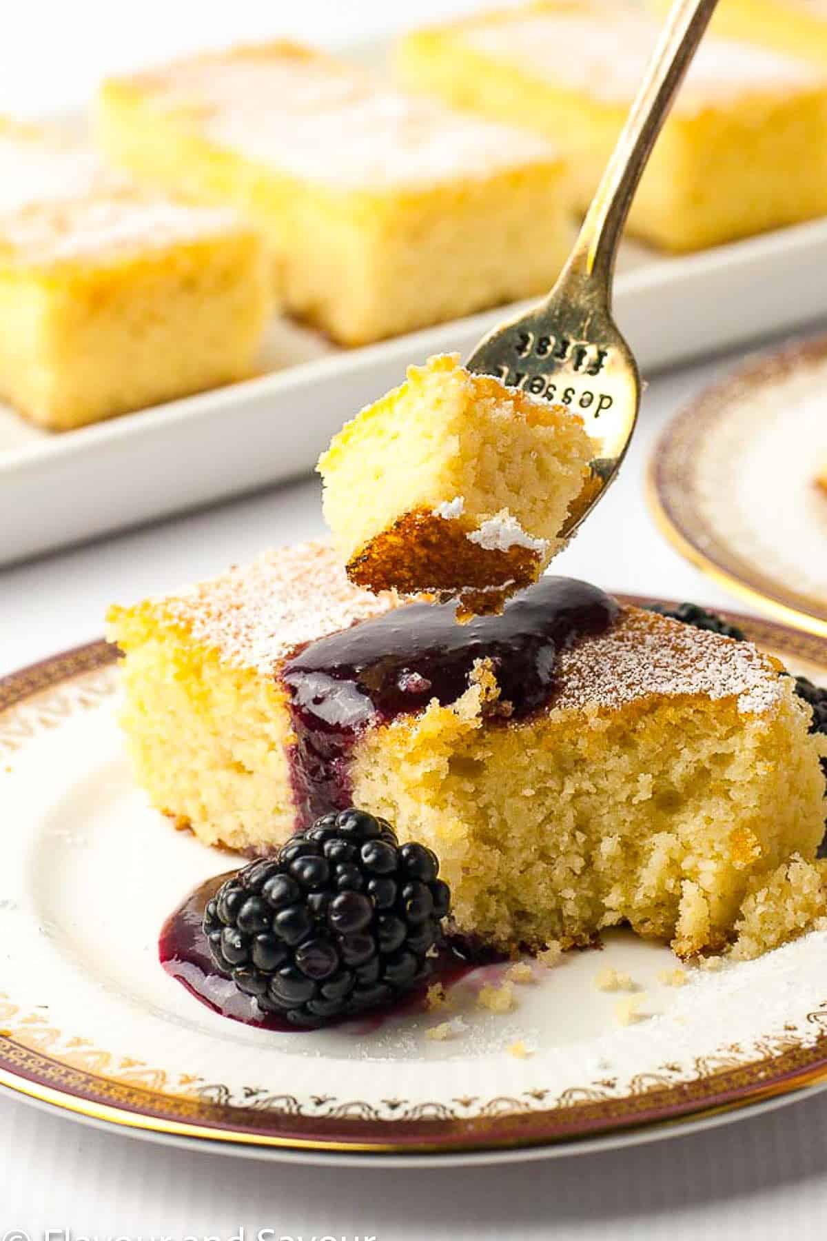 A forkful of gluten-free lemon ricotta cake with blackberry sauce and fresh blackberries.