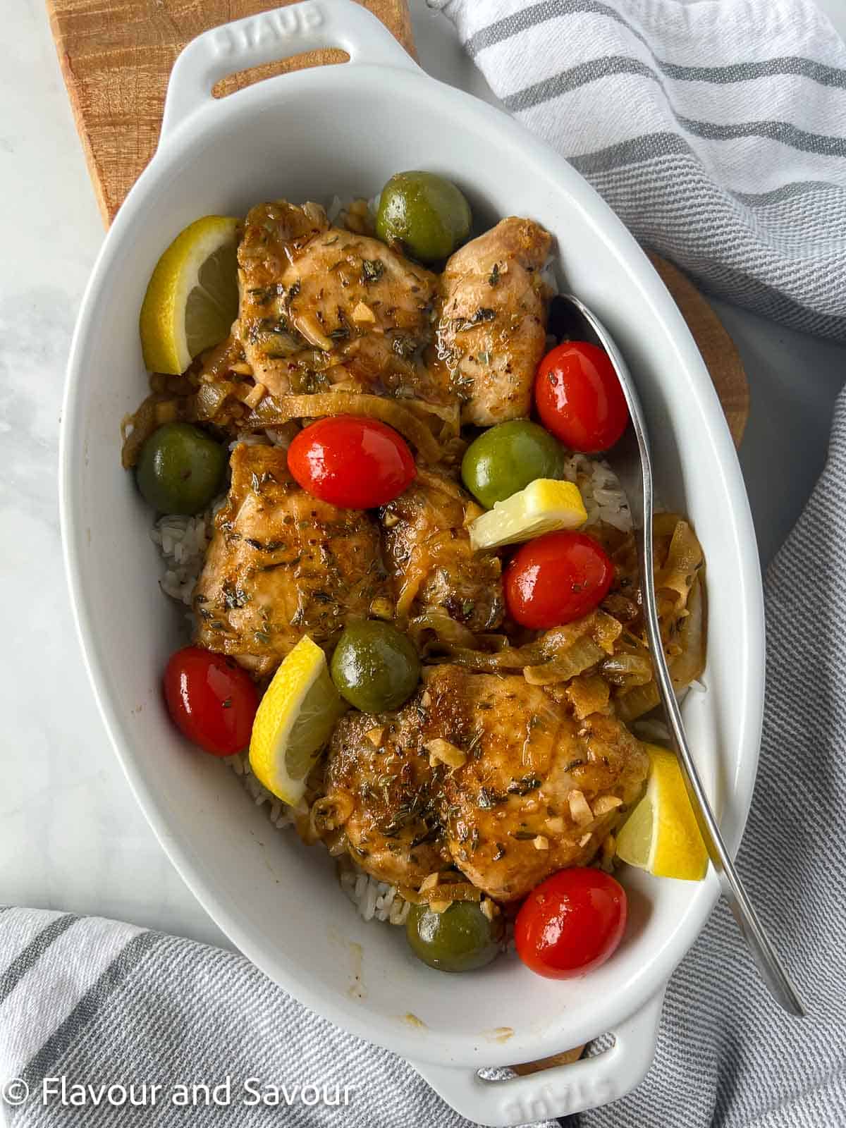 Overhead view of an oval baking dish with Moroccan lemon chicken thighs .