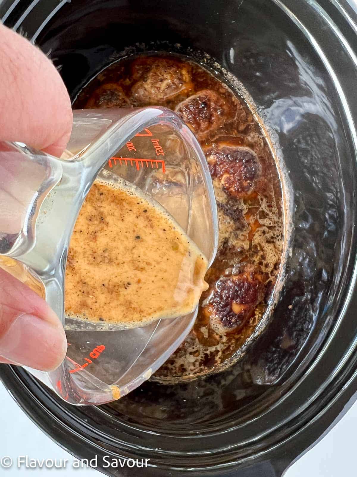 Adding cornstarch slurry to cooked chicken in a slow cooker.