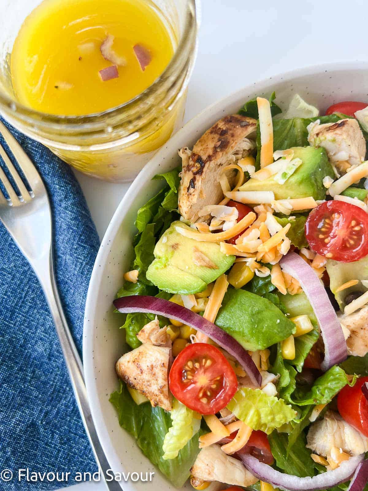 Chicken taco salad with a jar of zesty lime dressing.